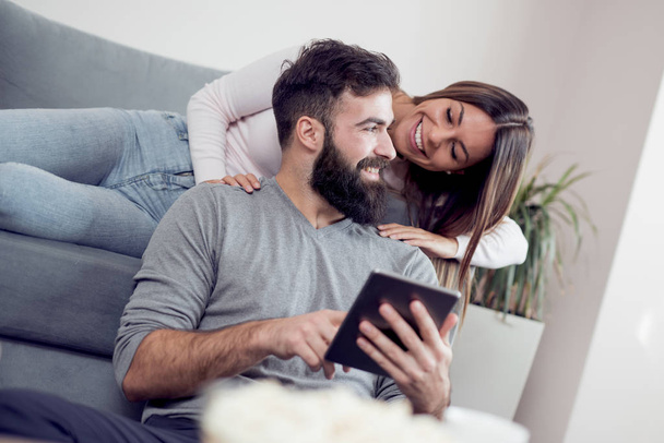 Fröhliches Paar nutzt Tablet-Computer und trinkt Kaffee - Foto, Bild