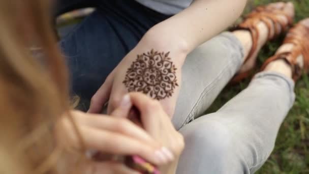 Mujer joven haciendo mehendi floral en una mano usando henna
. - Imágenes, Vídeo