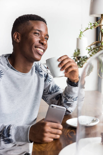 Pretoria, Afrique du Sud - 8 janvier 2018 : Un homme dans un café buvant du café et tenant un téléphone portable
. - Photo, image