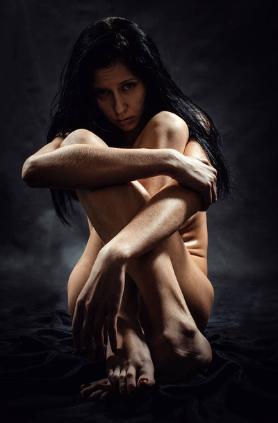 A mulher nua em um fundo preto
 - Foto, Imagem