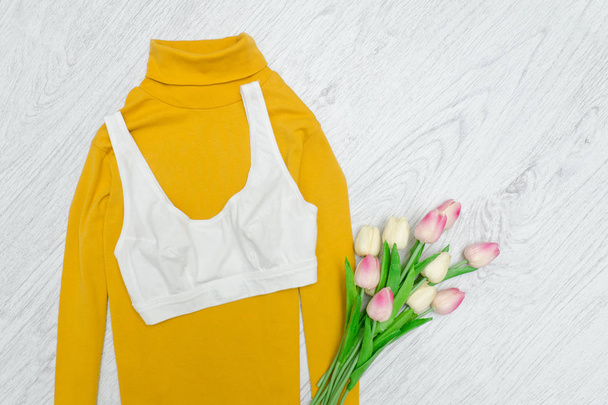 Parte superior blanca en cuello alto amarillo. Tulipanes rosados. Concepto de moda
 - Foto, Imagen