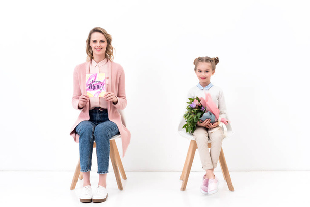 mother and daughter sitting on chairs and looking at camera on happy mothers day - Foto, Imagen