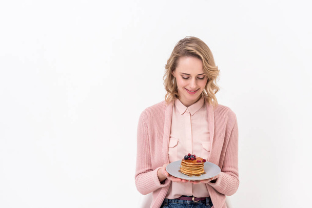 beautiful woman looking at pancakes on plate isolated on white - Valokuva, kuva
