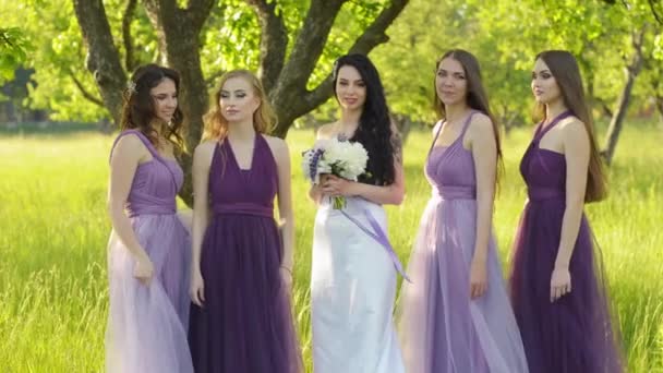 Damas de honor emocionales abrazando a la novia. Chicas caucásicas en vestidos de novia púrpura sonriendo y posando al aire libre
. - Imágenes, Vídeo