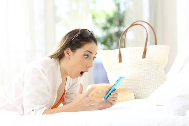 Amazed woman using a phone in summer vacations - Foto, Imagen