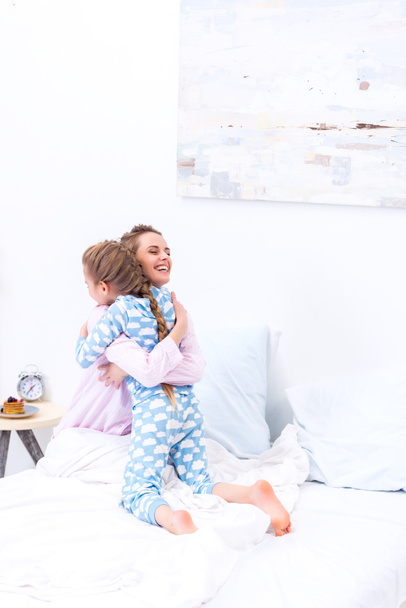 happy mother and daughter hugging in bedroom - Photo, Image