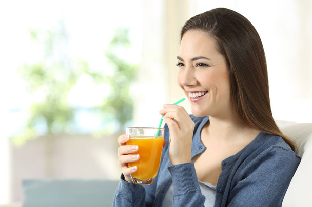 Happy girl holding an orange juice glass at home - Zdjęcie, obraz