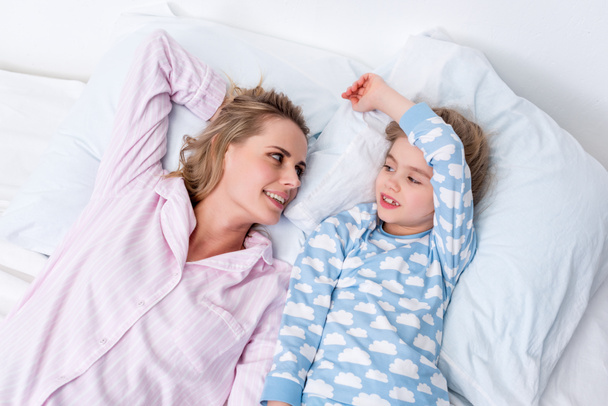 high angle view of happy mother and daughter lying on bed at home - Photo, image