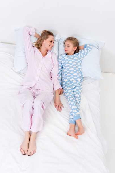 high angle view of mother and daughter lying on bed at home - Foto, imagen