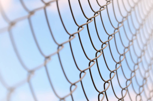 A photograph of a metal net used as a fence of private possessions. Old metal grid in perspective with a blurred background - Photo, Image