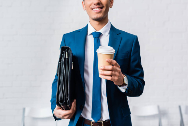 Smiling businessman holding briefcase and coffee cup - Фото, зображення