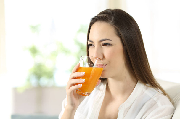 Woman drinking orange juice in a glass - Fotó, kép