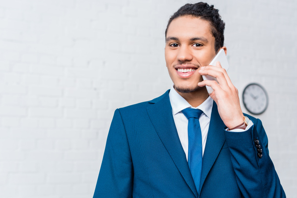 Молодой улыбающийся бизнесмен разговаривает по телефону
 - Фото, изображение