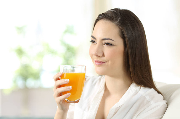 Woman holding a glass of orange juice at home - Fotoğraf, Görsel