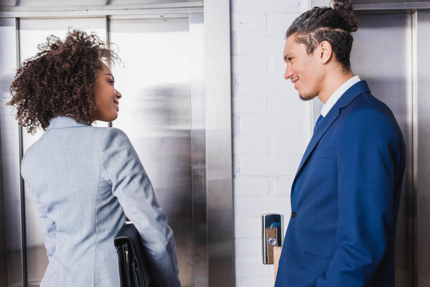 Χαμογελώντας Αφρικανικός Αμερικανός επιχειρηματίας και επιχειρηματίας μιλάει με ασανσέρ - Φωτογραφία, εικόνα