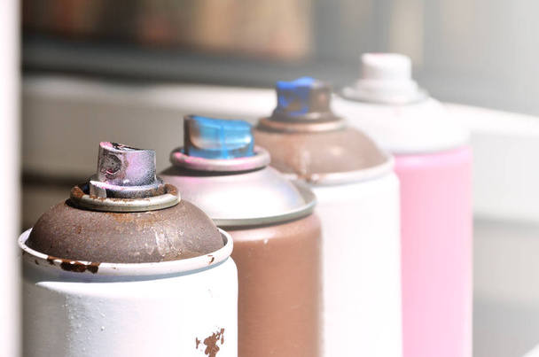 A few used aerosol paint sprayers lie on the windowsill in the workshop of a graffiti artist. The concept of street art and illegal drawing on the walls. Youth hobby - Photo, Image
