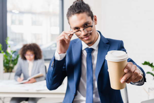 Улыбающийся бизнесмен предлагает кофе в бумажной чашке
 - Фото, изображение