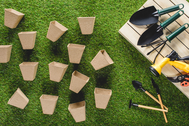 top view of gardening equipment and pile of flower pots on grass  - Photo, Image