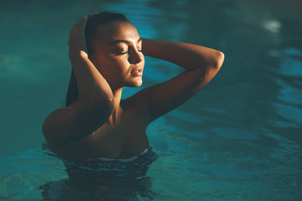 Молода приваблива жінка насолоджується відкритим басейном в літній час
 - Фото, зображення