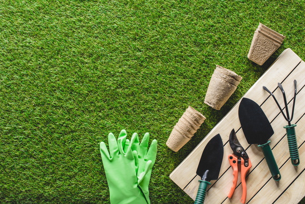 top view of protective gloves, flower pots and gardening tools on grass - Photo, Image