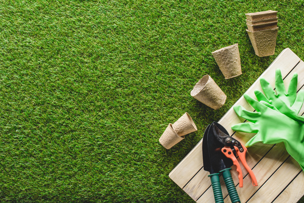 vista superior de macetas, guantes de protección y herramientas de jardinería en la hierba
 - Foto, Imagen