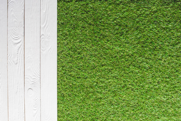 top view of green lawn and white wooden planks background  - Foto, afbeelding