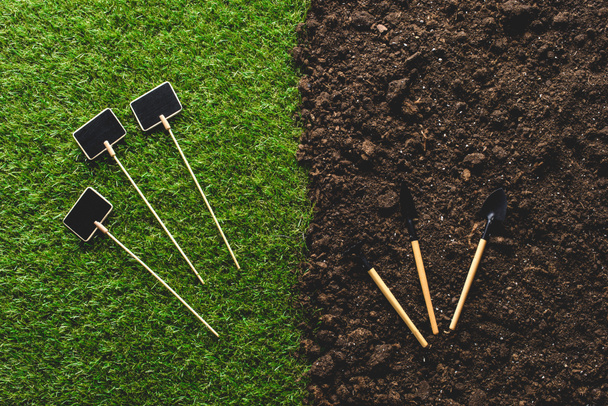 top view of empty blackboards on grass and gardening tools on soil  - Photo, Image