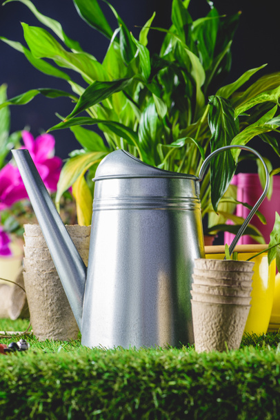 closeup view of watering can and flower pots on grass  - Photo, Image