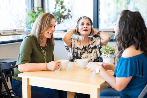 Lächelnde Freundinnen entspannen sich in einem Café und unterhalten sich beim Kaffeetrinken - Foto, Bild