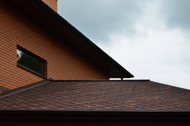 The house is equipped with high-quality roofing of shingles (bitumen tiles). A good example of perfect roofing. The roof is reliably protected from adverse weather conditions - Photo, Image