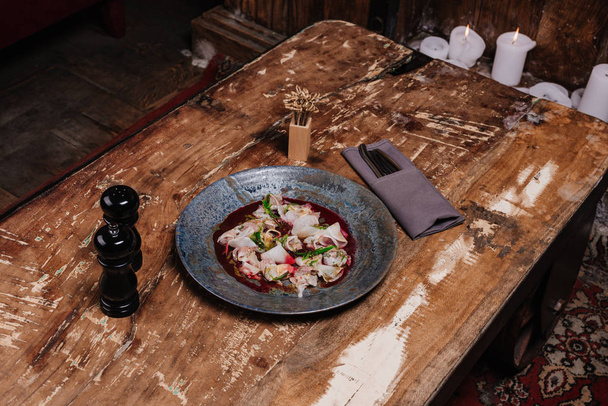 a fából készült asztal étteremben friss, ízletes étvágygerjesztõnek dorado és daikon magas szög, kilátás - Fotó, kép