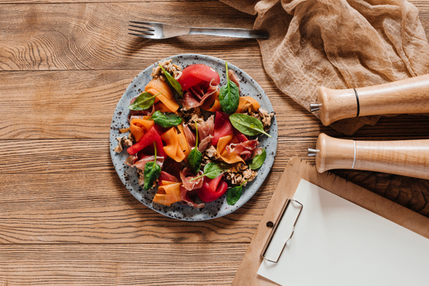 vista superior de deliciosa ensalada con mejillones, verduras de raíz y jamón en la mesa de madera
 - Foto, Imagen