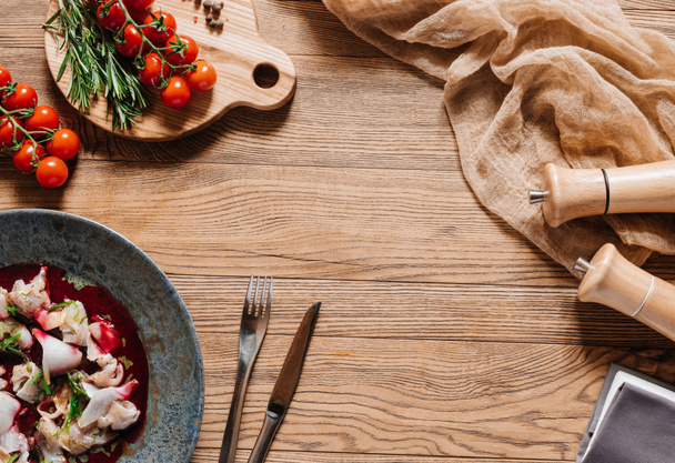 Widok góry Ceviche z dorado, widelec i nóż, świeże pomidory i przyprawy na drewnianym stole - Zdjęcie, obraz
