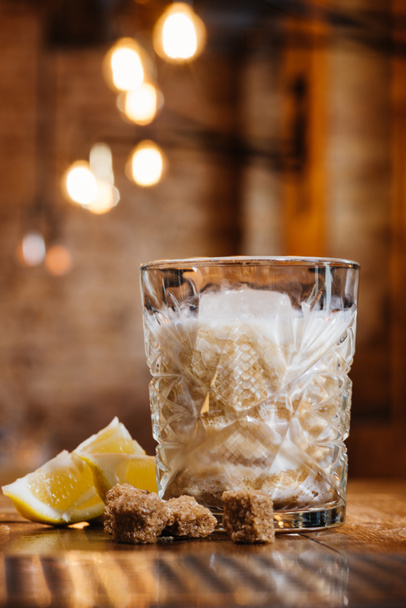 close-up view of glass with cream alcohol cocktail, lemon and brown sugar on wooden table - Photo, Image