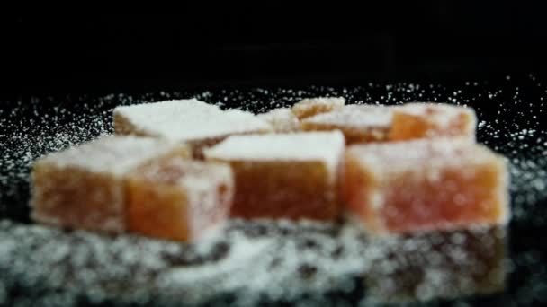 focus in op verspreide sinaasappel marmelade groep bedekt met suiker op zwarte spiegel achtergrond - Video