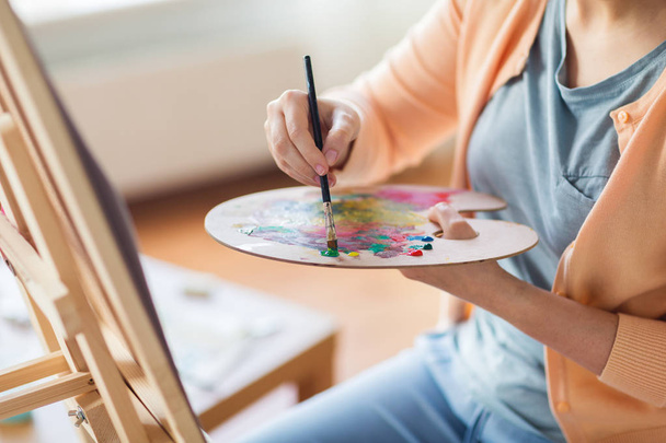 artist with palette and brush painting at studio - Φωτογραφία, εικόνα