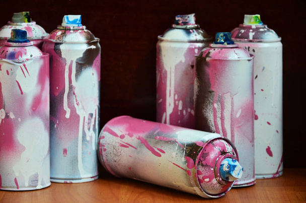 Bodegón con un gran número de coloridas latas de aerosol de pintura en aerosol en la superficie de madera tratada en el taller de graffiti del artista. Latas sucias y manchadas para pulverizar arte
 - Foto, imagen