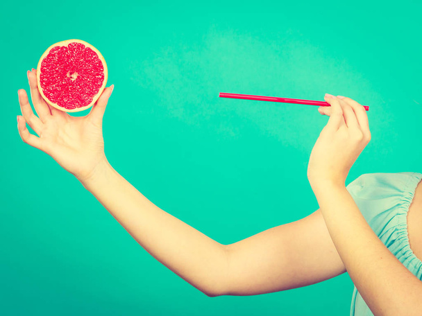 Woman drinking juice from fruit, red grapefruit - Foto, imagen