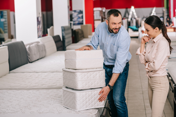 couple with folding mattresses in furniture store with arranged mattresses  - Photo, Image