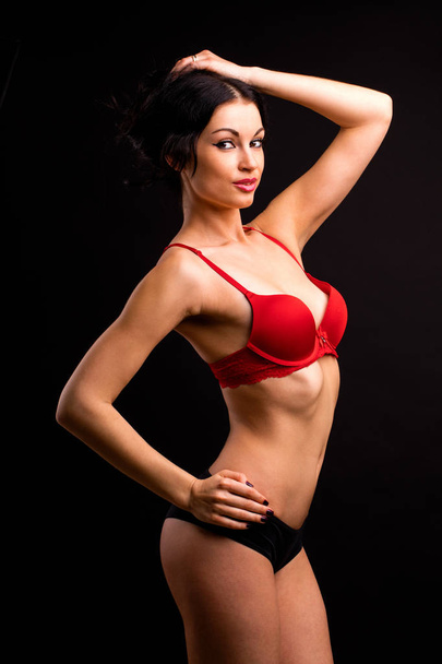 Portrait of sexy brunette woman in red and black underwear on a  - Foto, Imagen
