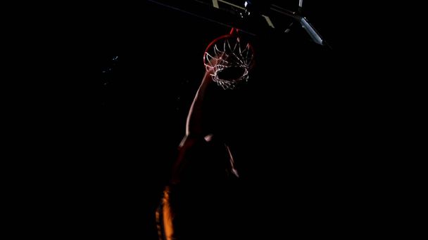 Nahaufnahme eines Basketball-Dunks. Werfen Sie in einem Basketballkorb auf dem Hintergrund der gelben Scheinwerfer, der Ball trifft den Ring ist, was durch das Netz fliegen. Basketball in Reifen, Zeitlupe - Foto, Bild