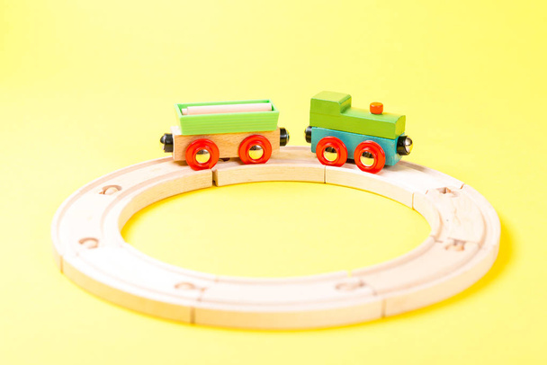 Дерев'яний іграшковий поїзд встановлений на доріжках на жовтому тлі
. - Фото, зображення