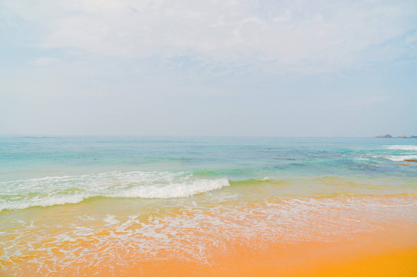 Blauwe golven van de Oceaan en geel zand van het strand. - Foto, afbeelding