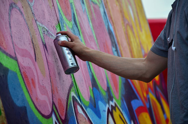 Μια νεαρή κοκκινομάλλα γκράφιτι καλλιτέχνης ζωγραφίζει ένα νέο γκράφιτι στον τοίχο. Φωτογραφία από τη διαδικασία της σχεδίασης ένα γκράφιτι σε ένα τοίχο γκρο πλαν. Η έννοια της street art και παράνομη βανδαλισμού - Φωτογραφία, εικόνα