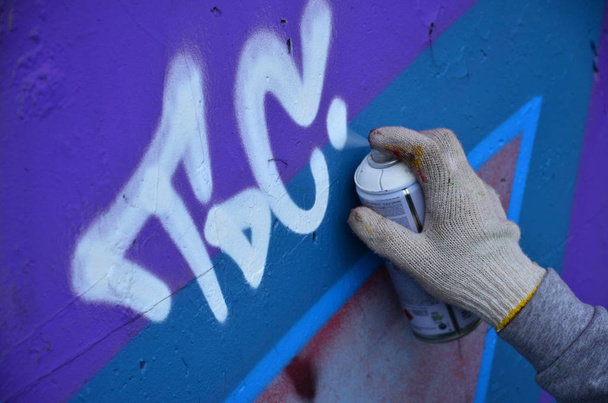 Bir el bir sprey ile yeni bir grafiti duvara çekiyor olabilir. Bir beton duvara yakın çekim bir grafiti çizim işlemi fotoğrafı. Sokak sanatı ve yasadışı vandalizm kavramı - Fotoğraf, Görsel