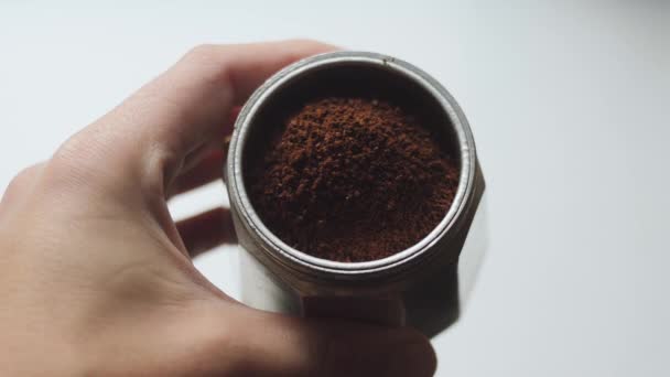 Demonstratie van de juiste slijpen van koffie voor de Italiaanse koffie-/ theevoorzieningen. Moka pot met donkere gebrande gemalen koffie in de menselijke hand. - Video