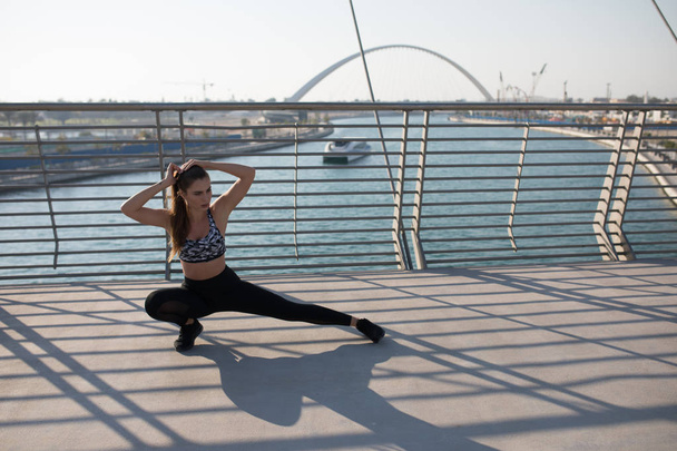 Sports woman doing stretching exercises on a bridge. - Foto, Imagem