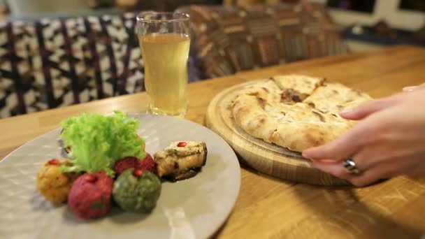 Woman hands takes a piece of traditional Georgian khachapuri dish with meat. Multi-colored Pkhali, Georgian dish with nuts and kubdari. - Footage, Video
