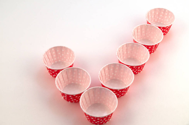 Kis papíron cupcakes a vörös szín a fehér borsó, meghatározott a formájában egy ketyeg (egy szimbólum a jóváhagyás). - Fotó, kép