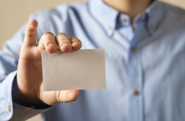 Man holding white business card on concrete wall background - Zdjęcie, obraz